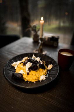 Siyah tabakta peynirli ve füme sosisli Mamaliga ve bir bardak kefir.Hominy. Moldova mutfağı kavramı.