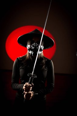 Maskeli ve geleneksel Japon başlıklı bir kadın Samuray kılıcıyla poz veriyor. Japon kültürü kavramı. Samuray. Katana.