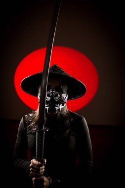 Maskeli ve geleneksel Japon başlıklı bir kadın Samuray kılıcıyla poz veriyor. Japon kültürü kavramı. Samuray. Katana.