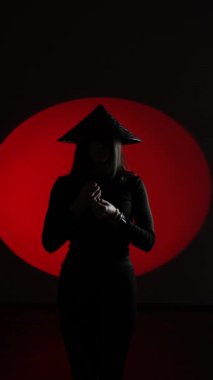 Ulusal Japon şapkalı bir kadın sugegasa Japon bayrağının arka planına karşı poz veriyor. Japon kültürü kavramı. Samuray. Dikey video