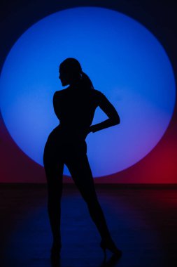 Mavi neon ışıkta dans eden bir kadının silueti. Mavi ışık çemberinde dans eden bir kadın. Dans ve hareket kavramı.