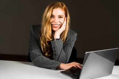 Kızıl saçlı genç bir kadın dizüstü bilgisayarda çalışıyor. Bir kız öğrenci dizüstü bilgisayarda çalışıyor. Uzaktan kumanda konsepti. Bir ofis çalışanının portresi.