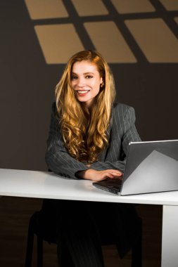 Kızıl saçlı genç bir kadın dizüstü bilgisayarda çalışıyor. Bir kız öğrenci dizüstü bilgisayarda çalışıyor. Uzaktan kumanda konsepti. Bir ofis çalışanının portresi.