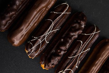 Siyah arka planda çikolata tüpleri. Farklı renkte tatlı dolgulu tüpler. Tatlılar konsepti