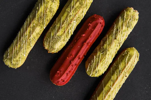 Siyah arka planda çikolata tüpleri. Farklı renkte tatlı dolgulu tüpler. Tatlılar konsepti