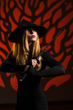 A woman in a black suit and sugegasa with a samurai sword poses against a mahogany background. Portrait of a samurai woman. Japanese culture concept clipart