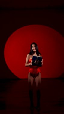 Kırmızı elbiseli neşeli bir kadınla tatil kutlaması. Kırmızı bir geçmişe karşı bir hediye. Çekici bir kadının ellerinde bir hediye. Noel konsepti. Noel hediyesi. Dikey video