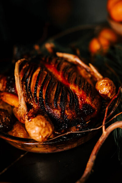 Жареная утка с соусом на рождественском фоне. Печёное мясо в духовке. Концепция рождественского стола. Низкий ключ