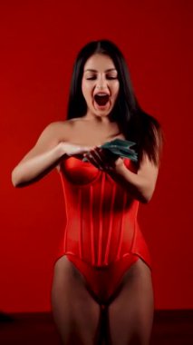 Kırmızı Giysili Kadın Canlı Kırmızı Arkaplanda Neşeli Bir Para Atar Başarı ve Özgüven Kutlaması. Dikey Video Konsepti.