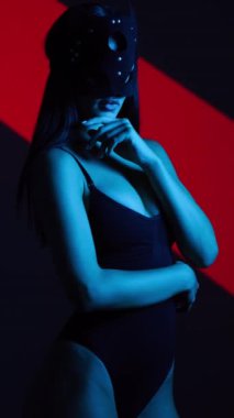 Neon ışıkta poz veren BDSM maskeli seksi kadın. BDSM konsepti. Sevgililer Günü. Kedi Kadın. Dikey video