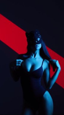 Neon ışıkta poz veren BDSM maskeli seksi kadın. BDSM konsepti. Sevgililer Günü. Kedi Kadın. Dikey video