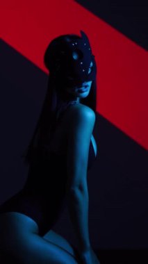 Neon ışıkta poz veren BDSM maskeli seksi kadın. BDSM konsepti. Sevgililer Günü. Kedi Kadın. Dikey video