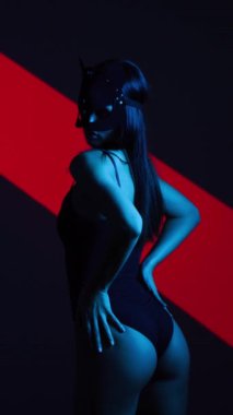 Neon ışıkta poz veren BDSM maskeli seksi kadın. BDSM konsepti. Sevgililer Günü. Kedi Kadın. Dikey video