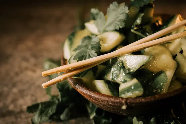 Salatalık turşusu taze maydanozlu ve otlu, lezzetli bir aşçılık deneyimi için suşi çubuklarıyla geliştirilmiş bir köy tabağında servis edilir.