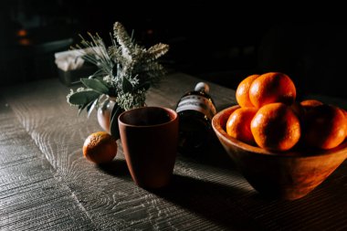 Craft Glass of Mulled Wine Beside a Bowl of Tangerines on a Rustic Wooden Table During the Festive Season clipart