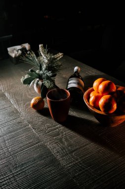 Craft Glass of Mulled Wine Beside a Bowl of Tangerines on a Rustic Wooden Table During the Festive Season clipart