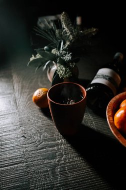 Craft Glass of Mulled Wine Beside a Bowl of Tangerines on a Rustic Wooden Table During the Festive Season clipart