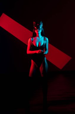 Ellerinde kelepçe olan kedi maskeli bir kadın. Vücut giysili seksi bir kadının portresi. BDSM konsepti. Sevgililer Günü.