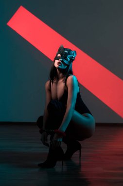 Ellerinde kelepçe olan kedi maskeli bir kadın. Vücut giysili seksi bir kadının portresi. BDSM konsepti. Sevgililer Günü.