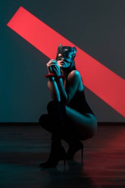 Ellerinde kelepçe olan kedi maskeli bir kadın. Vücut giysili seksi bir kadının portresi. BDSM konsepti. Sevgililer Günü.