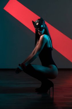 Ellerinde kelepçe olan kedi maskeli bir kadın. Vücut giysili seksi bir kadının portresi. BDSM konsepti. Sevgililer Günü.