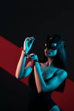 Ellerinde kelepçe olan kedi maskeli bir kadın. Vücut giysili seksi bir kadının portresi. BDSM konsepti. Sevgililer Günü.