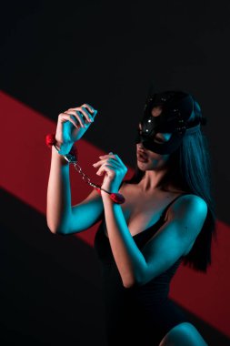 Ellerinde kelepçe olan kedi maskeli bir kadın. Vücut giysili seksi bir kadının portresi. BDSM konsepti. Sevgililer Günü.