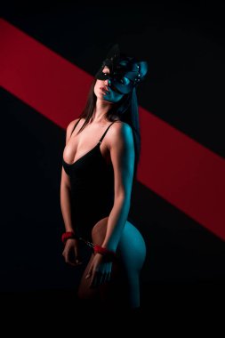 Ellerinde kelepçe olan kedi maskeli bir kadın. Vücut giysili seksi bir kadının portresi. BDSM konsepti. Sevgililer Günü.