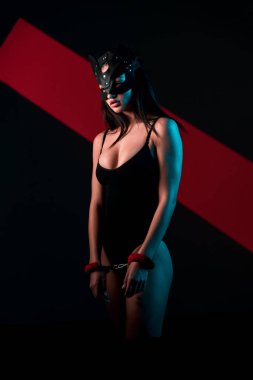 Ellerinde kelepçe olan kedi maskeli bir kadın. Vücut giysili seksi bir kadının portresi. BDSM konsepti. Sevgililer Günü.
