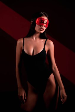 Siyah elbiseli seksi bir kadın. Uyku maskesi takmış. Üzerinde seksi yazılar var.