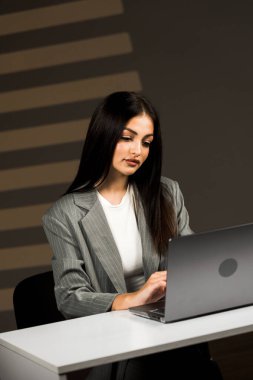 Young business woman working with laptop in modern office during daytime.Online work concept.Portrait of office worker.Woman with laptop clipart