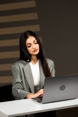 Young business woman working with laptop in modern office during daytime.Online work concept.Portrait of office worker.Woman with laptop clipart