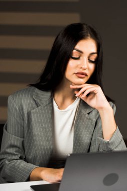 Young business woman working with laptop in modern office during daytime.Online work concept.Portrait of office worker.Woman with laptop clipart