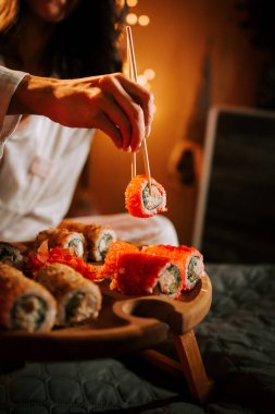 Noel ağacının arka planında suşi yiyen bir kadın. Noel seti. Suşi. Tatil suşi konsepti