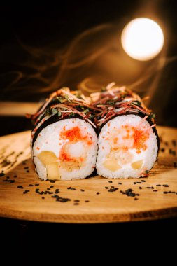 Ahşap bir tahtanın üzerinde deniz ürünleri ve otlarla dolu taze rulo ve dağınık eşlenik. Suşi konsepti. Japon mutfağı kavramı