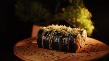 Lezzetli suşi ruloları ahşap bir tahtanın üzerinde döner. Canlı renklerde taze malzemeler sergiler.