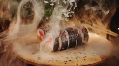 Lezzetli suşi ruloları ahşap bir tahtanın üzerinde döner. Canlı renklerde taze malzemeler sergiler.