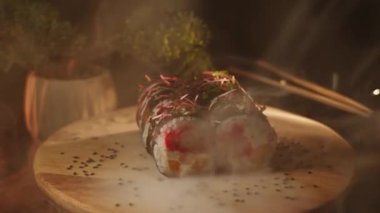 Lezzetli suşi ruloları ahşap bir tahtanın üzerinde döner. Canlı renklerde taze malzemeler sergiler.