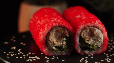 Lezzetli suşi ruloları ahşap bir tahtanın üzerinde döner. Canlı renklerde taze malzemeler sergiler.