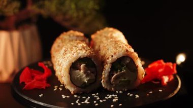 Suşi siyah arka planda döner. Lezzetli Japon suşisi hazır ve nazır. Taze unagi suşi ve somon ve Philadelphia peynirli rulo..
