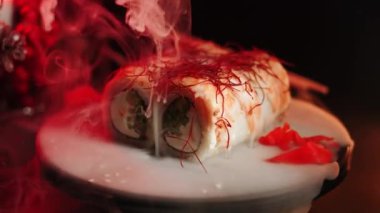 Suşi siyah arka planda döner. Lezzetli Japon suşisi hazır ve nazır. Taze unagi suşi ve somon ve Philadelphia peynirli rulo..