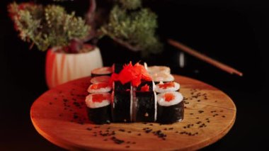 Suşi siyah arka planda döner. Lezzetli Japon suşisi hazır ve nazır. Taze unagi suşi ve somon ve Philadelphia peynirli rulo..