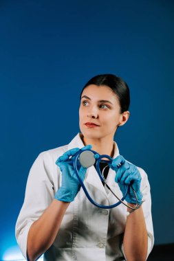 Portrait of a woman pediatric doctor in a white coat with a stethoscope against a blue background showcasing her dedication to children's health clipart