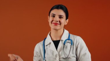 Beyaz önlüklü kadın doktor ve turuncu arka planda duran steteskop.