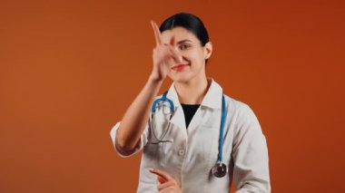 Beyaz önlüklü kadın doktor ve turuncu arka planda duran steteskop.