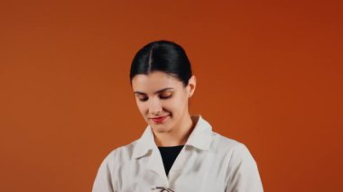 Beyaz önlüklü kadın doktor ve turuncu arka planda duran steteskop.