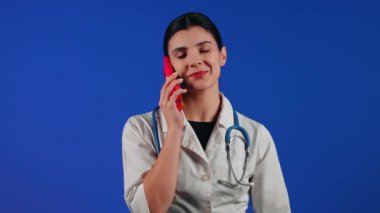 Beyaz önlüklü bir kadın çocuk doktorunun portresi mavi arka planda tıbbi muayeneye hazırlanıyor.