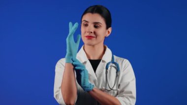 Beyaz önlüklü bir kadın çocuk doktorunun portresi mavi arka planda tıbbi muayeneye hazırlanıyor.