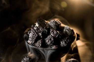 Koyu bir arkaplana karşı zengin dokusunu vurgulayan bir tabakta kurumuş kuru eriklerin yakın plan görüntüsü