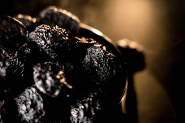 Koyu bir arkaplana karşı zengin dokusunu vurgulayan bir tabakta kurumuş kuru eriklerin yakın plan görüntüsü
